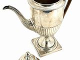 a silver tea pot and a silver cup on a table