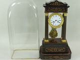 une horloge posée sur la table, sous un dôme en verre