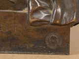 bronze statue of a man sitting on a bench with a hat on his head