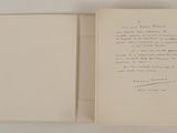 an open book with a handwritten poem on it sitting on top of a table
