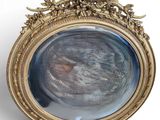 un cadre ovale en or avec, au centre, le portrait d'un homme