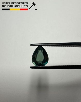 a close up of a pair of pliers holding a green diamond