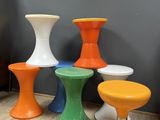 four different colored stools sitting on a wooden floor