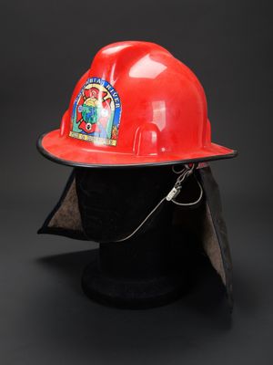 un casque de pompier rouge posé sur une tête de mannequin noire