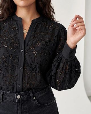 une femme vêtue d'un t-shirt noir et d'un jean, posant pour une photo