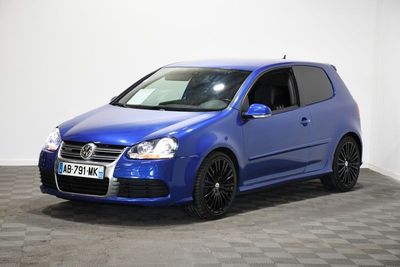 Une Volkswagen Golf bleue est garée dans une pièce dont le sol est en damier.