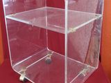 clear acrylic display case with wheels on a red surface
