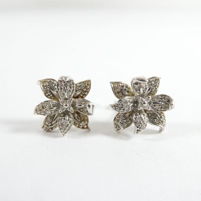 une paire de boucles d'oreilles en forme de fleur en diamant sur fond blanc