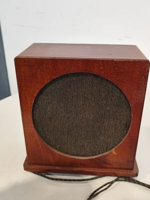 une petite enceinte en bois posée sur une table, avec un cordon