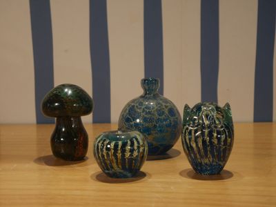 trois vases posés sur une table en bois, avec un mur rayé en arrière-plan