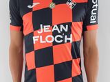 Cet homme porte un t-shirt rouge et noir et un short noir.
