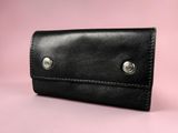 a black leather wallet on a pink background