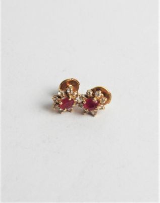a pair of red and gold earrings on a white surface