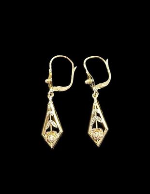 a pair of gold earrings on a black background