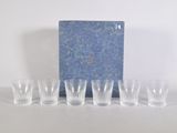 six verres à shot et un livre bleu posés sur une table