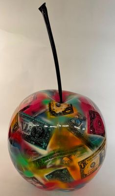 une pomme en verre sur laquelle est posé beaucoup d'argent
