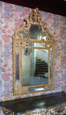 a mirror and a table in a room with a wallpapered wall