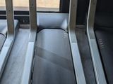 two tread machines sit in front of a window in a gym