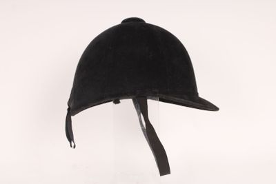 Le casque est noir et comporte un lanière en cuir autour de la visière.