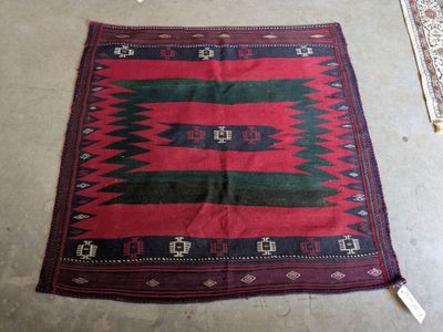 a red, green and black rug on the floor next to a rug