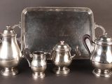 a silver tray with silver teapots and a tray with silver cups