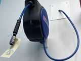 un tuyau bleu fixé à un mur blanc, à côté d'un interrupteur
