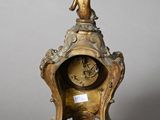 a gold clock with a statue on top of it