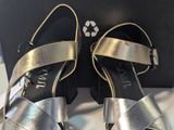 une paire de sandales argentées pour femme, présentées dans une boîte
