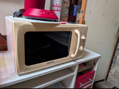 a microwave sitting on top of a table with a red hat on top