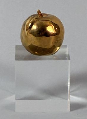 a gold apple sitting on a clear stand