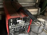 a red and black welding machine sitting in a garage
