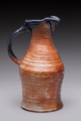 a brown vase with a blue handle sitting on a table