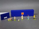 figurines représentant des personnes et des animaux debout devant une boîte bleue
