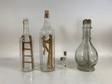 trois bouteilles en verre contenant des figurines miniatures, posées sur une table