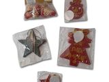 five christmas decorations in plastic bags on a white surface
