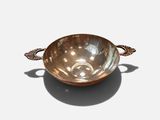a metal bowl with a handle on a white surface