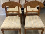 two wooden chairs with upholstered seats in front of a white curtain