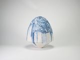 un vase bleu et blanc posé sur une surface blanche