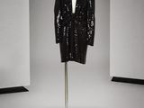 une photo d'une veste noire à paillettes posée sur un présentoir pour mannequin