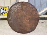 an old rusty plate sitting on the ground next to a sign