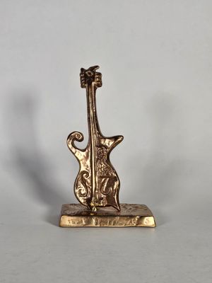 une guitare dorée posée sur un support, sur une surface blanche