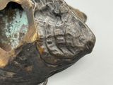 une statue en bronze représentant un poisson avec un trou dans la bouche