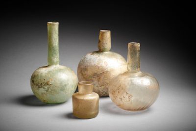 Plusieurs vases en verre sont posés sur une table devant un fond noir.