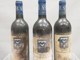 trois bouteilles de vin sont posées sur une vitrine