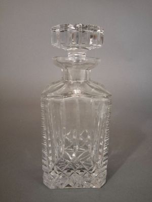 une bouteille en verre transparent munie d'un bouchon, posée sur une table