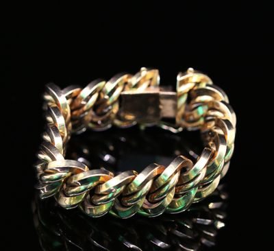 un gros plan d'un bracelet doré et vert posé sur une surface noire