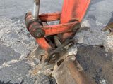 a red excavator sitting on the side of the road
