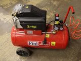 a red air compressor sitting on the floor in the garage
