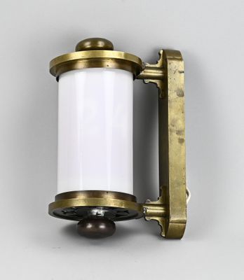 a close up of a brass and white light fixture on a wall