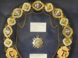 a gold chain with a medal on it in a glass case